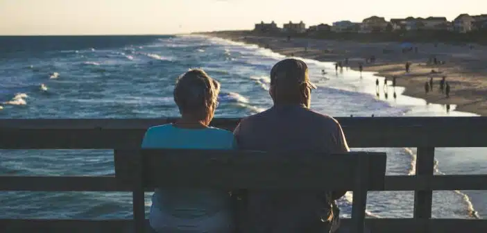 man and woman sitting on bench in front of beach