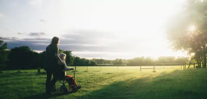 woman standing next to woman riding wheelchair